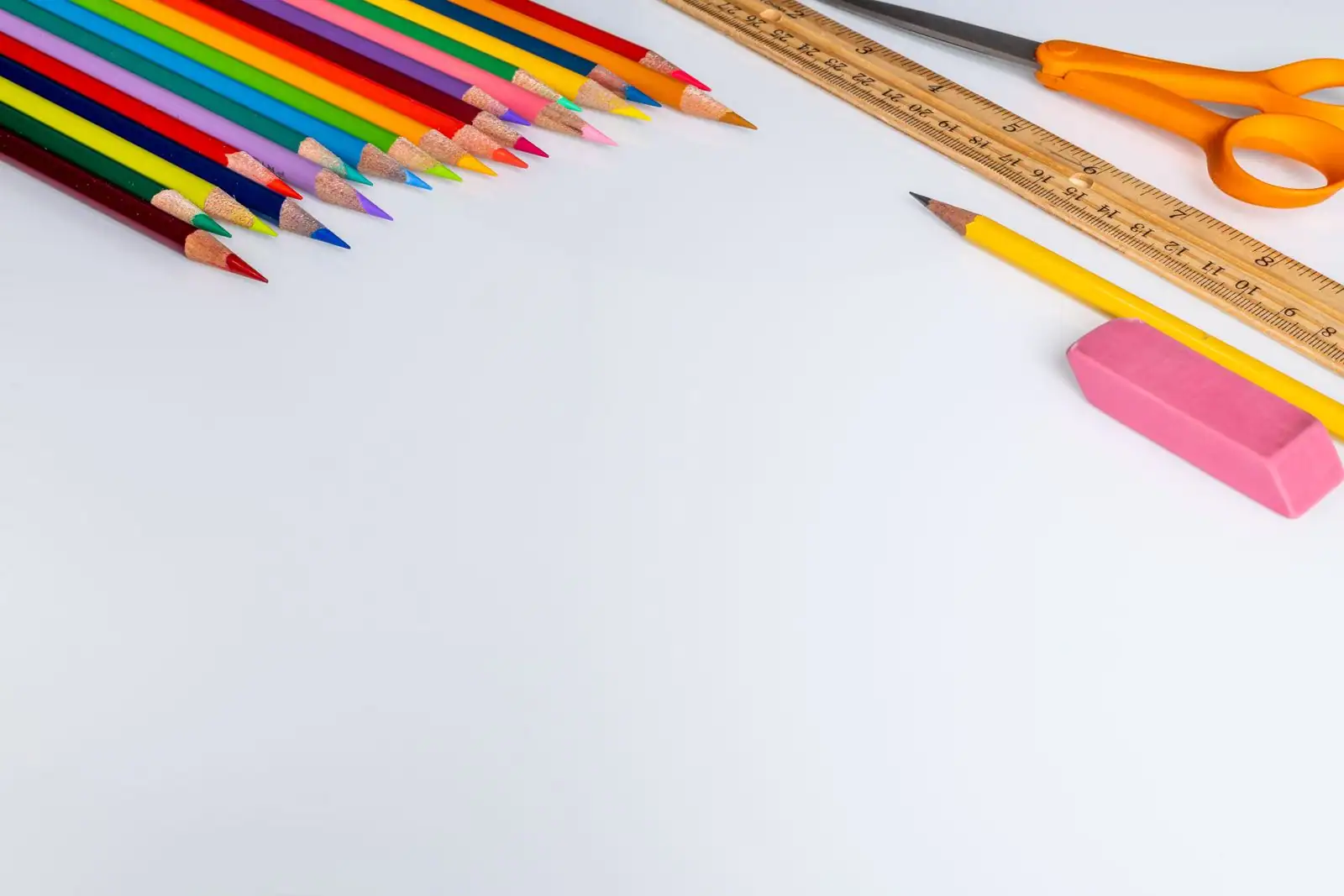Crayons de couleur, crayon à papier, gomme, règle et ciseaux sur fond blanc