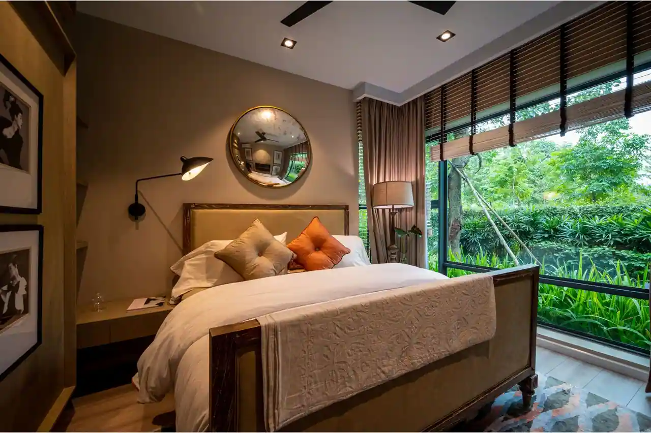 Chambre chaleureuse avec un lit perpendiculaire à une grande fenêtre ouverte sur un jardin verdoyant