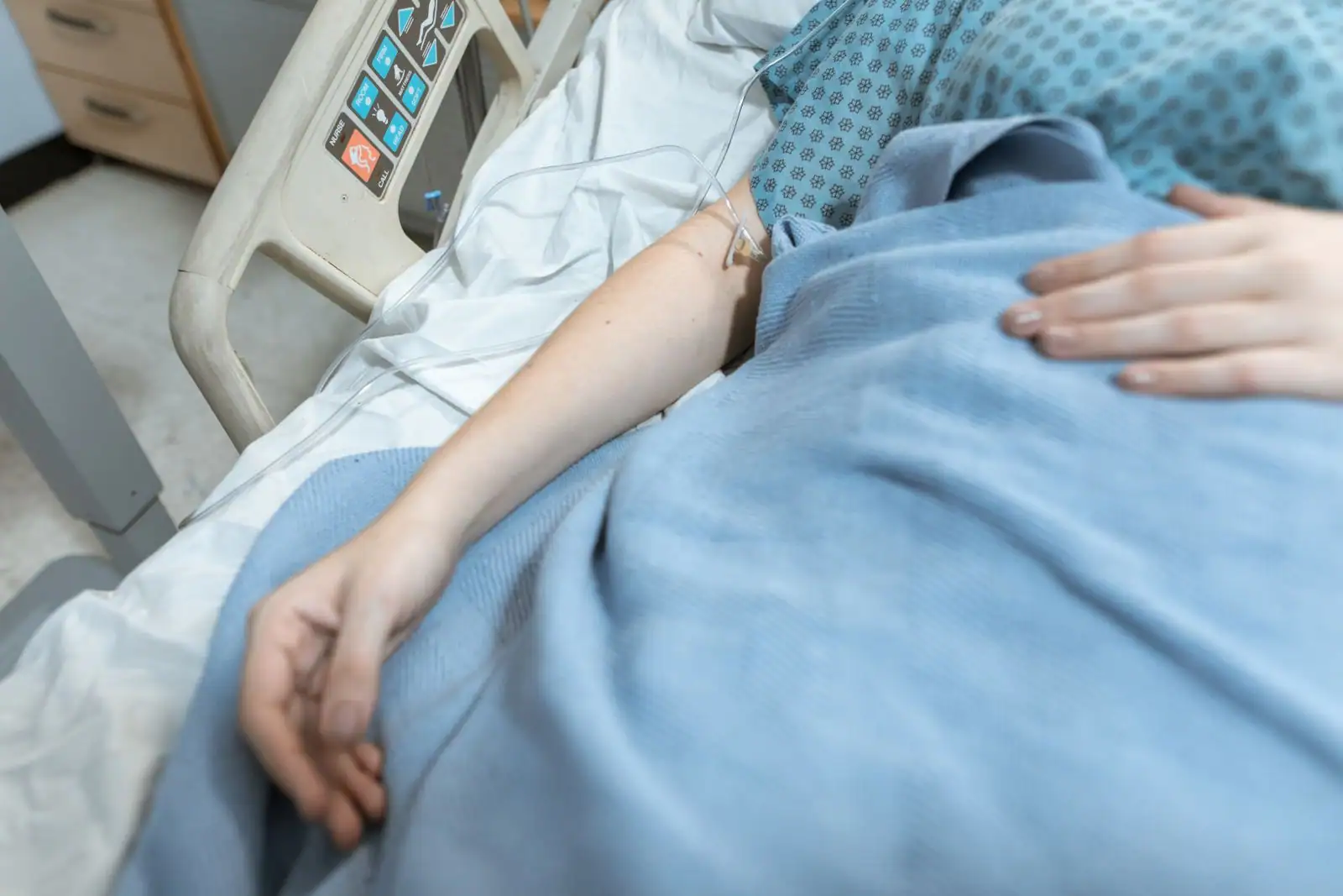 Patient alité en milieu hospitalier relié à une perfusion au bras, image illustrative d'un traitement par voie veineuse