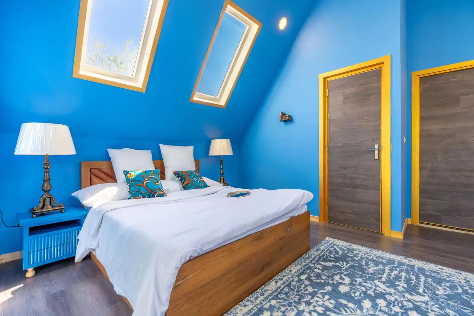 Chambre aménagée sous les combles, lit placé sous la pente du toit et fenêtre de toit