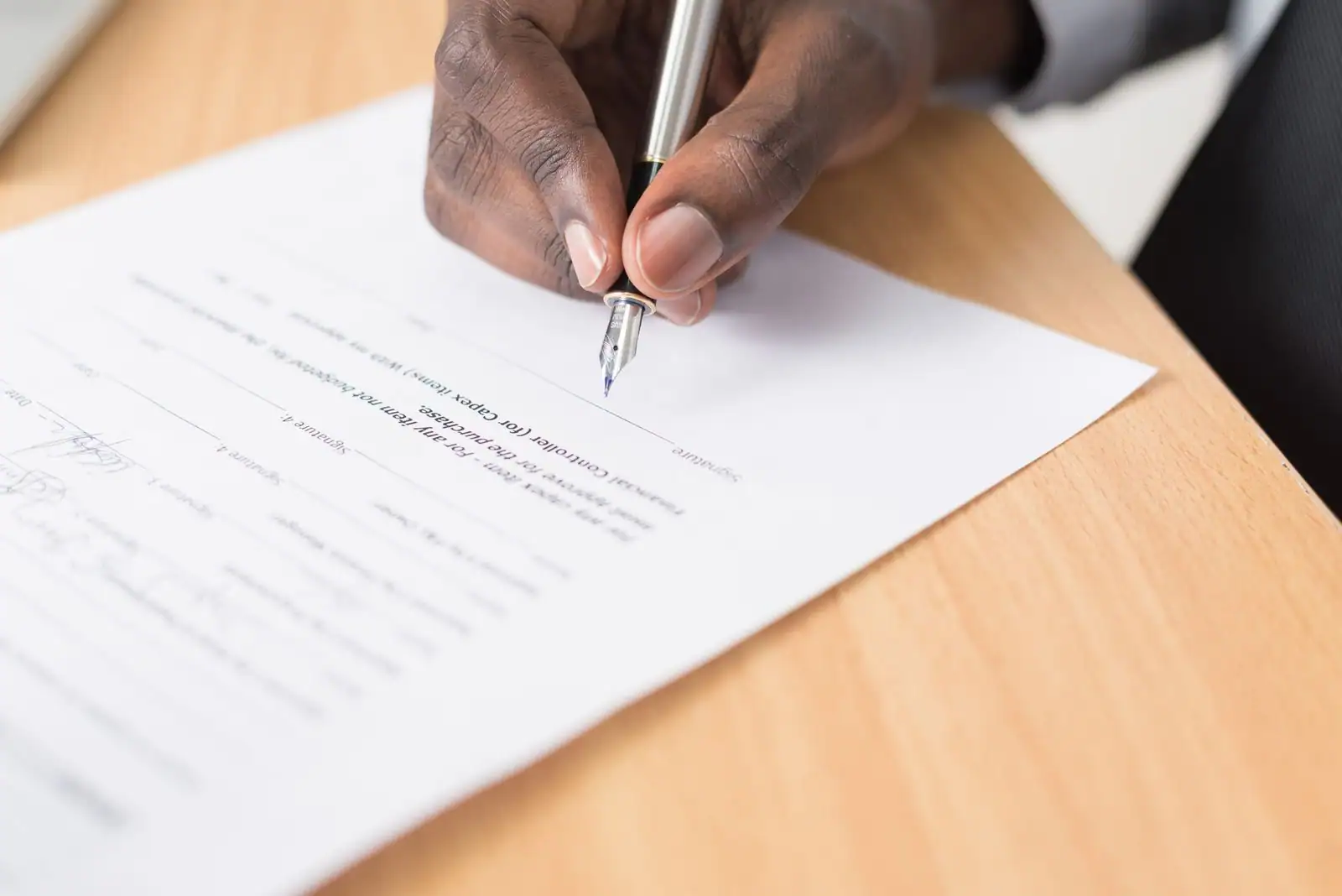 Signature de documents administratifs sur un bureau avec un stylo, évoquant un acte notarié
