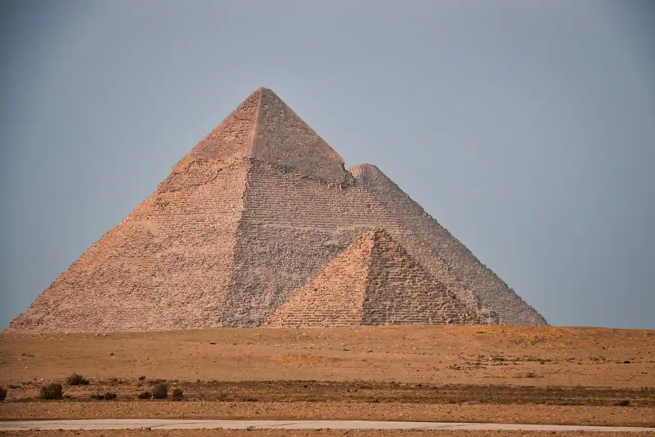 Pyramides de Gizeh en pierre se détachant sur un ciel dégagé, dans le désert égyptien.
