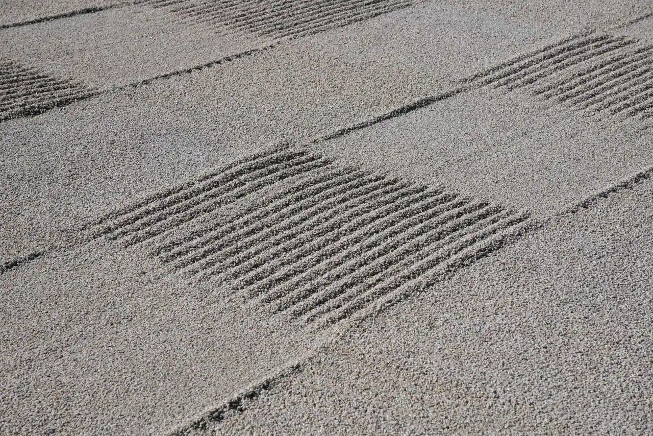 Gravier clair finement ratissé en motifs croisés, comme dans un jardin zen de style japonais.