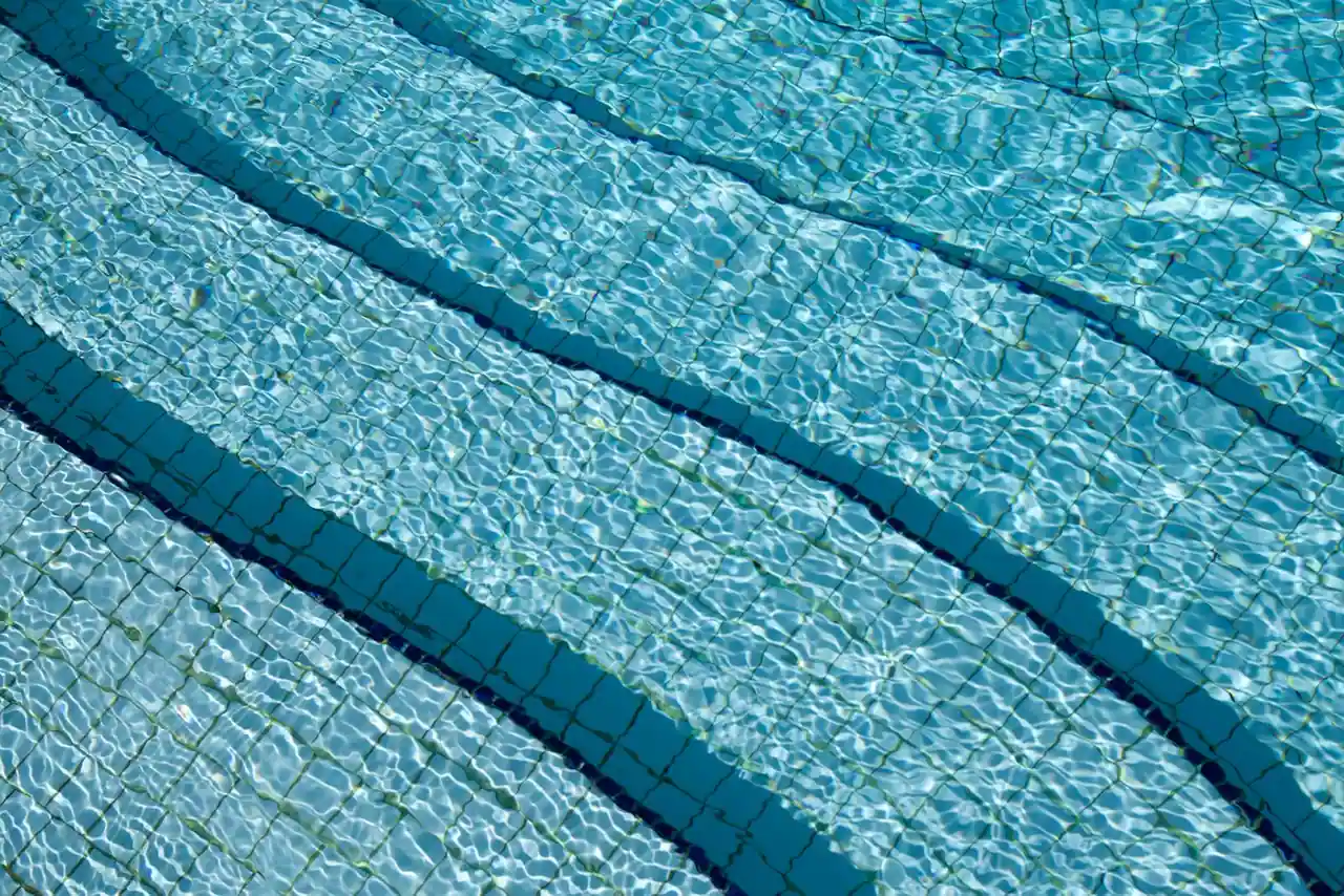 Eau claire et turquoise d'une piscine extérieure carrelée avec marches immergées, bassin bien entretenu.