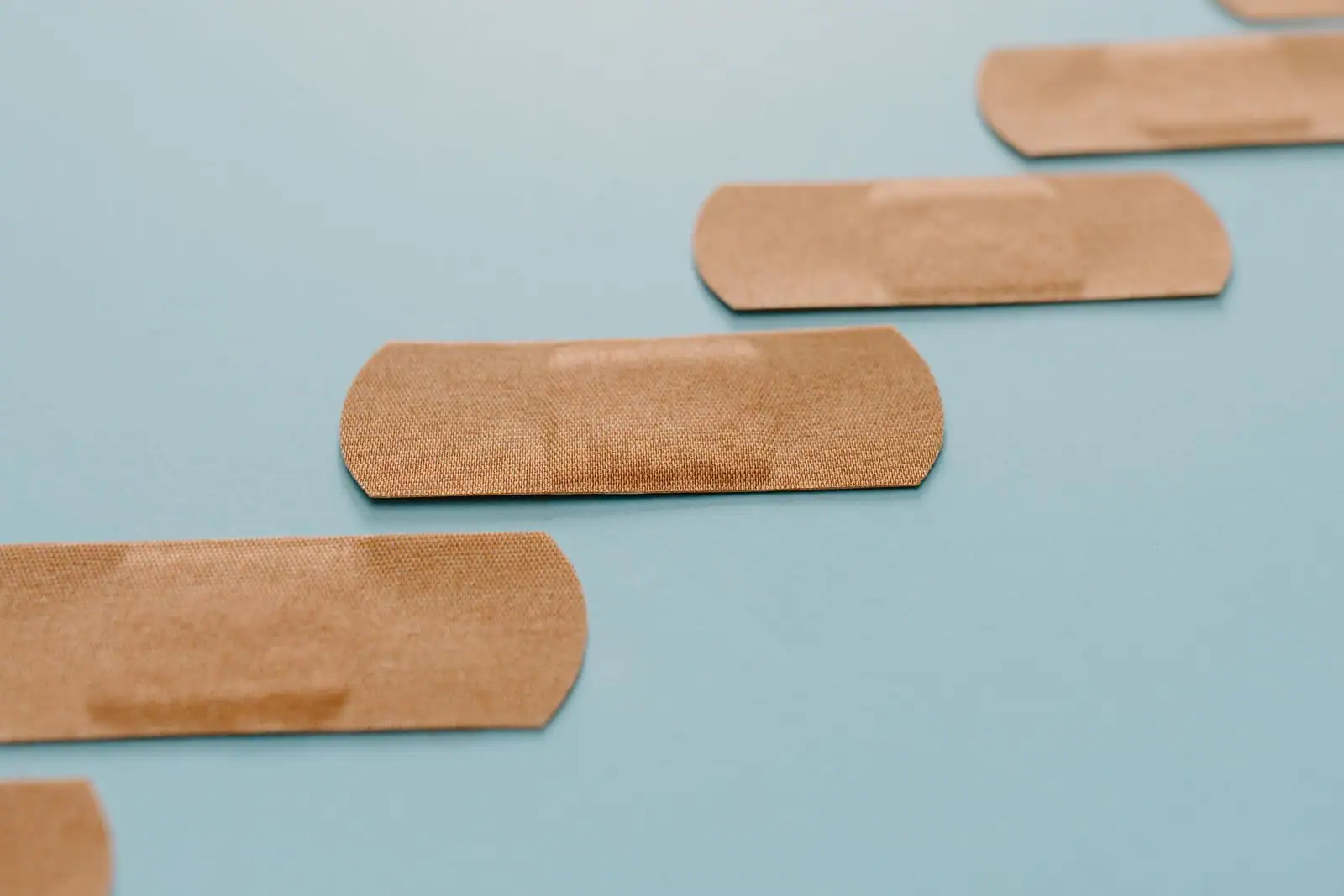 Plusieurs pansements adhésifs disposés sur un fond bleu clair