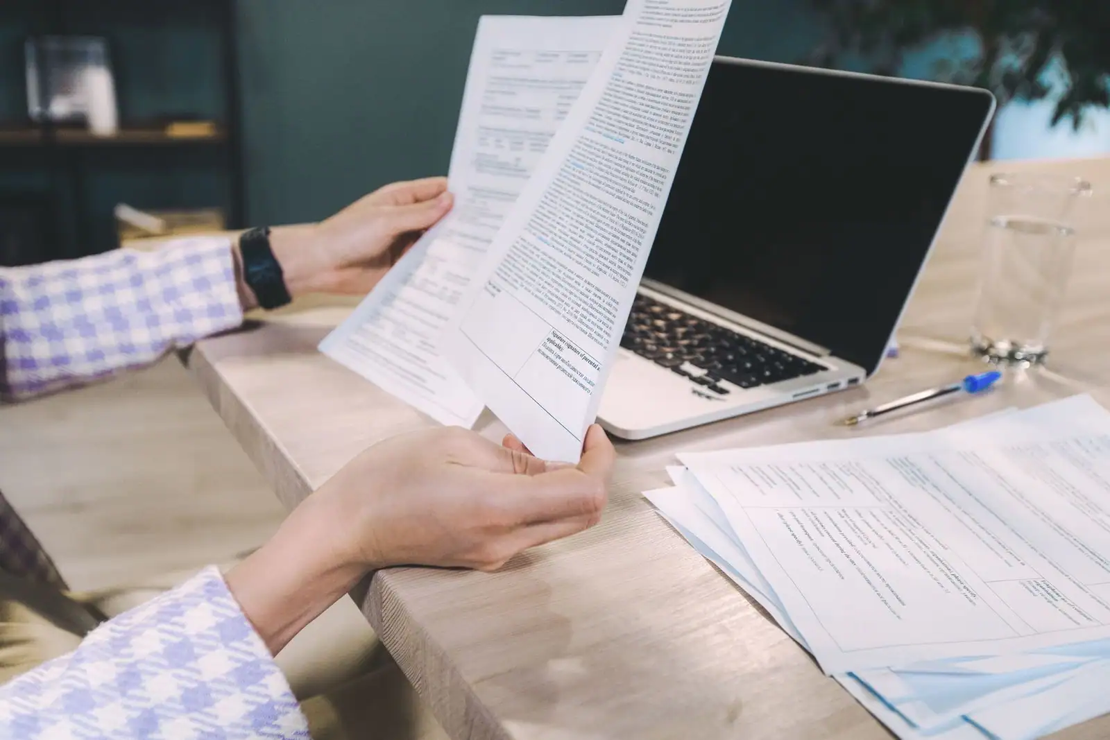 Mains examinant des documents de location à un bureau, devant un ordinateur portable