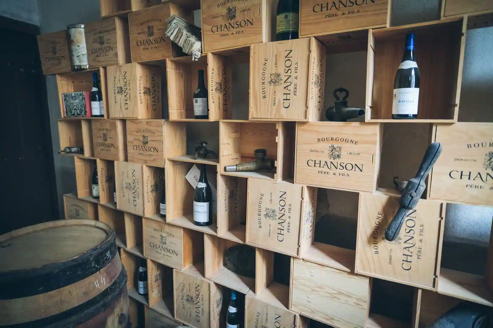 Mur composé de caisses de vin en bois gravées, empilées pour former des étagères et des niches de rangement.