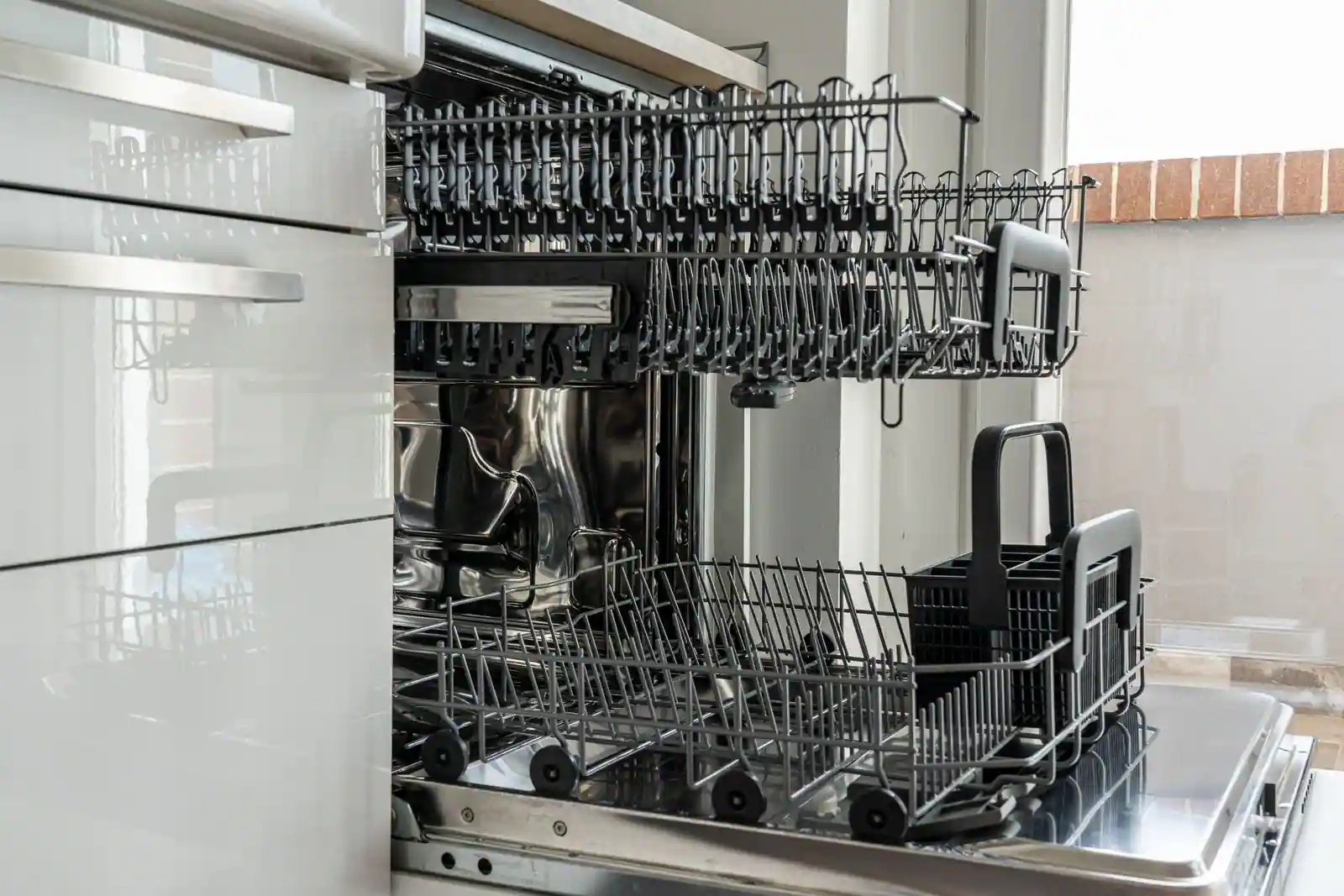 Lave-vaisselle encastrable ouvert, paniers et panier à couverts visibles dans une cuisine moderne