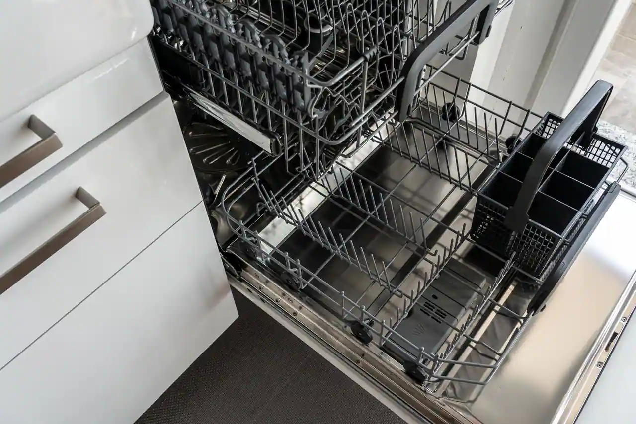 Lave-vaisselle encastrable ouvert, paniers inférieur et supérieur sortis, fond de cuve en inox visible.