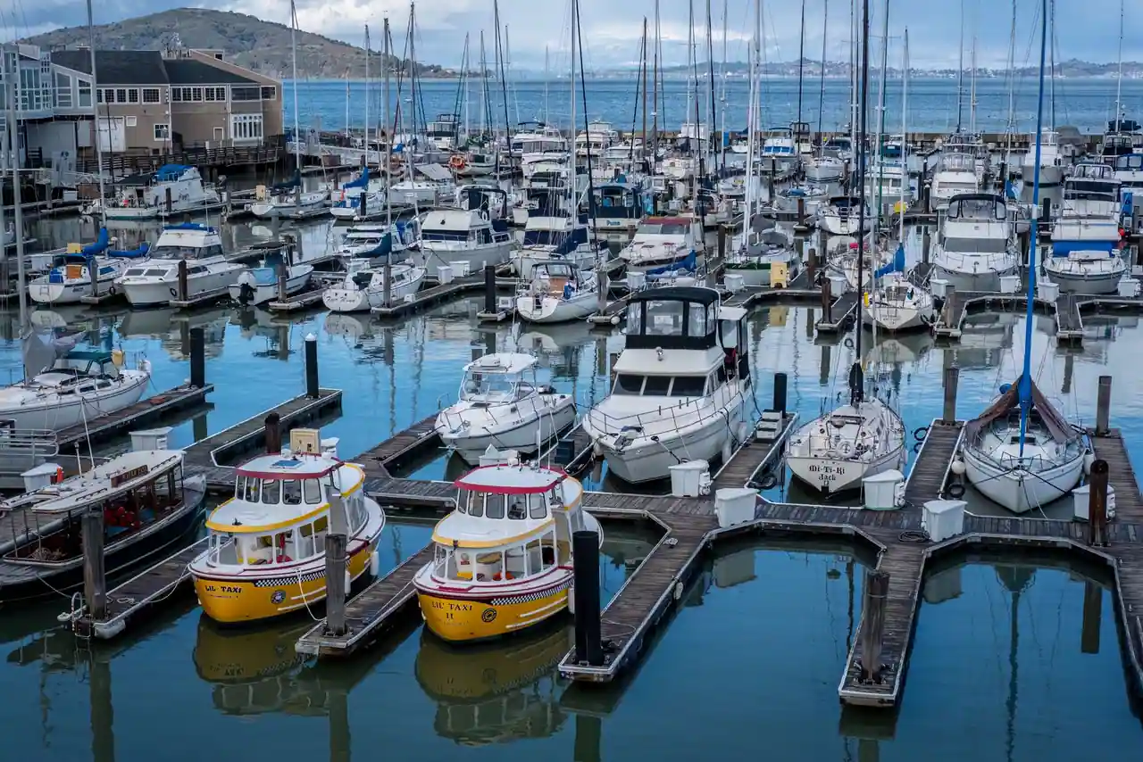 Des bateaux de plaisance amarrés aux pontons d'un port de plaisance, sur une eau calme.