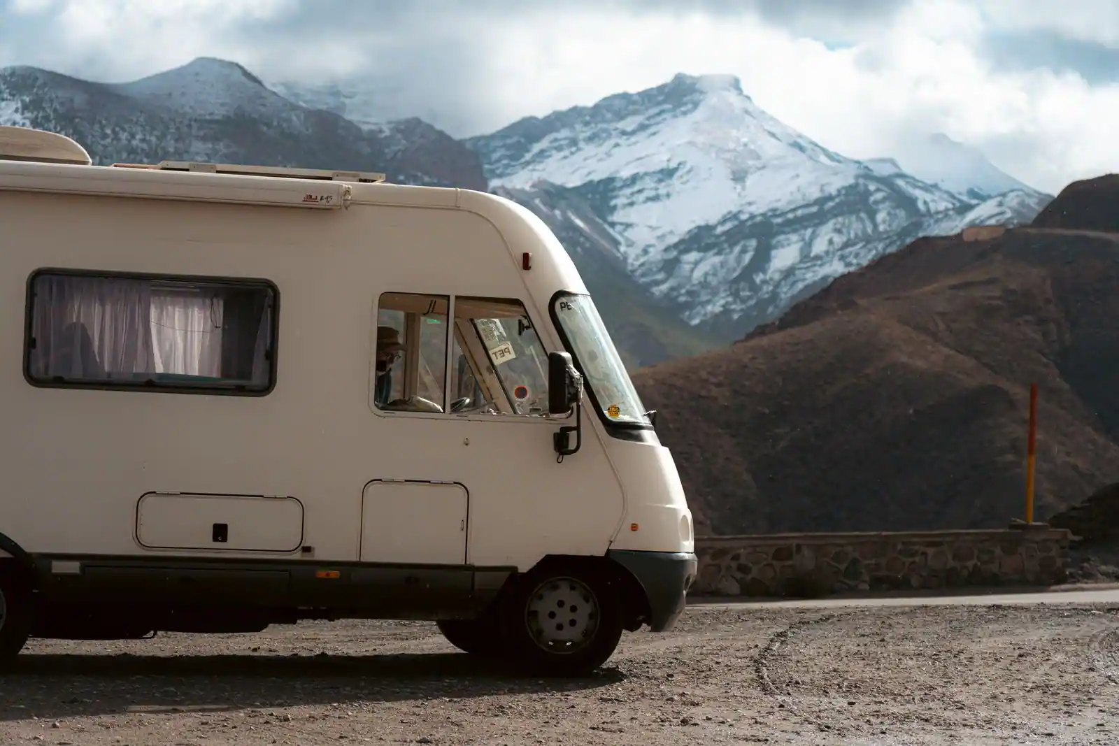 Camping-car intégral blanc sur une route de montagne enneigée, lors d'un voyage en itinérance