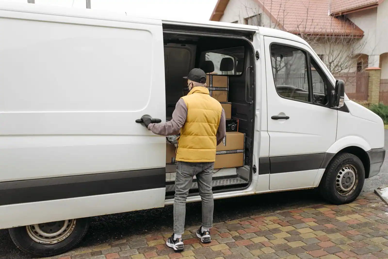 Personne chargeant des cartons dans un fourgon utilitaire blanc à la porte latérale ouverte
