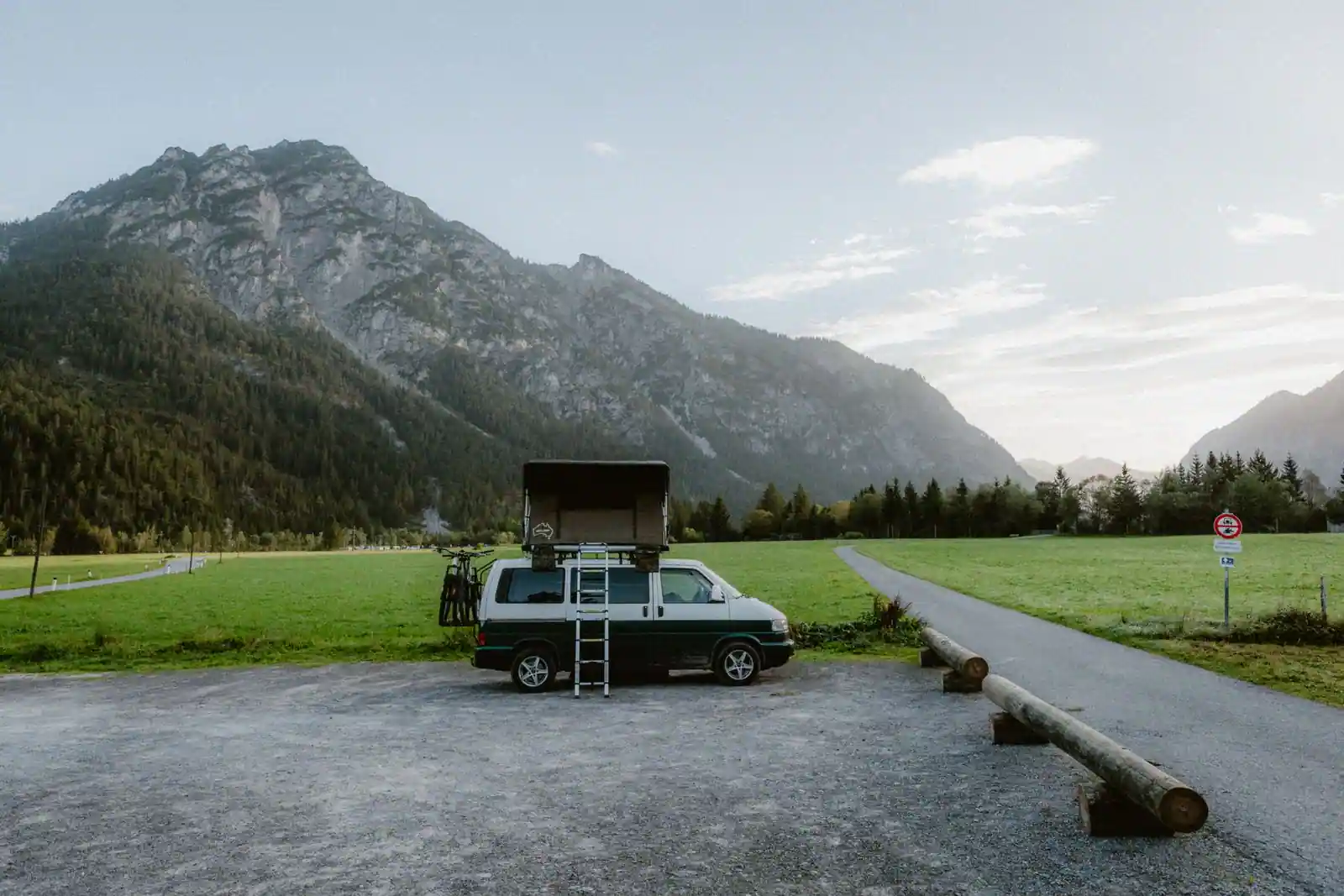 Fourgon aménagé avec toit relevable ouvert, garé devant des montagnes dans un cadre naturel
