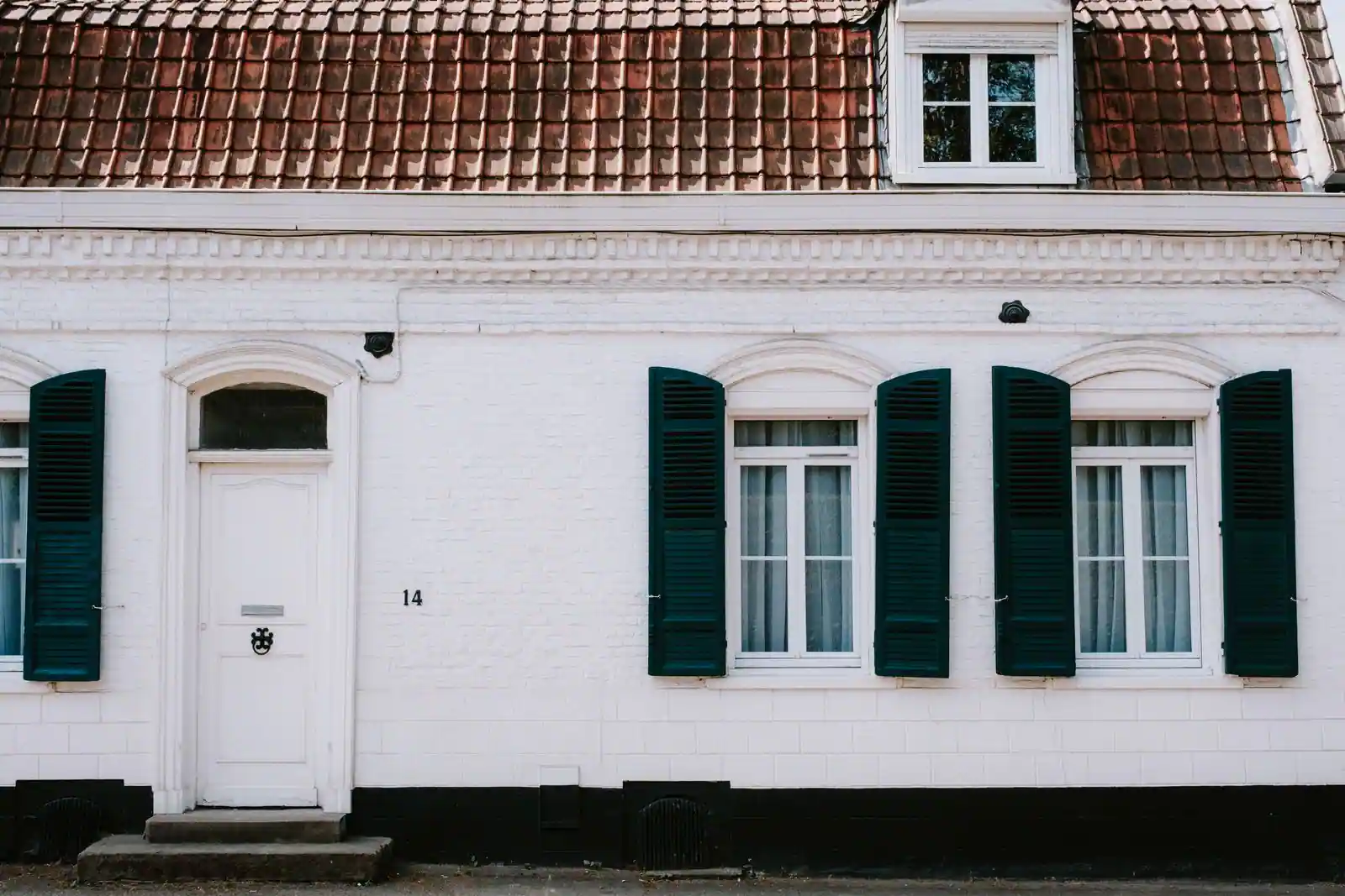 Maison blanche aux volets vert foncé, typique des villages de la côte atlantique