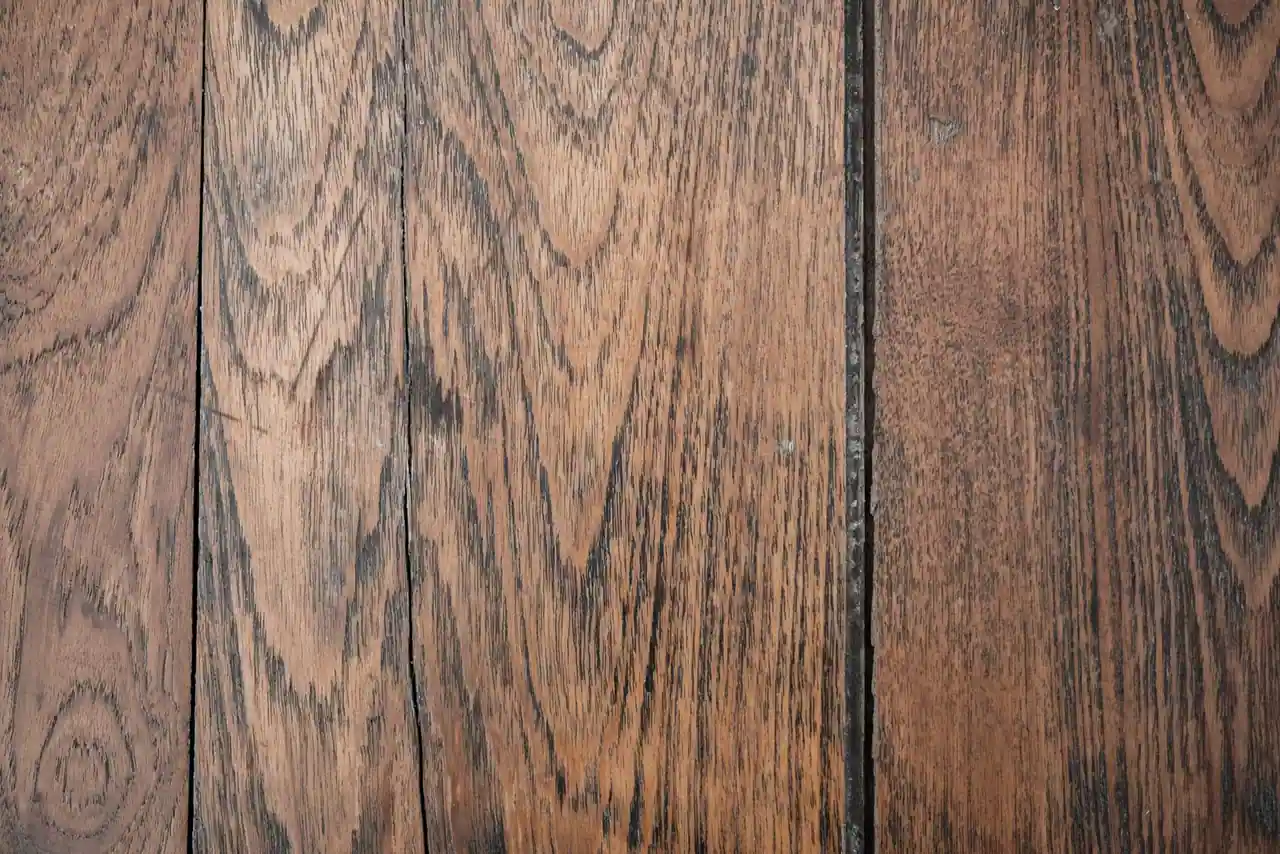 Lames d'un vieux parquet en bois marquées par l'usure et les rayures, à rénover par ponçage.