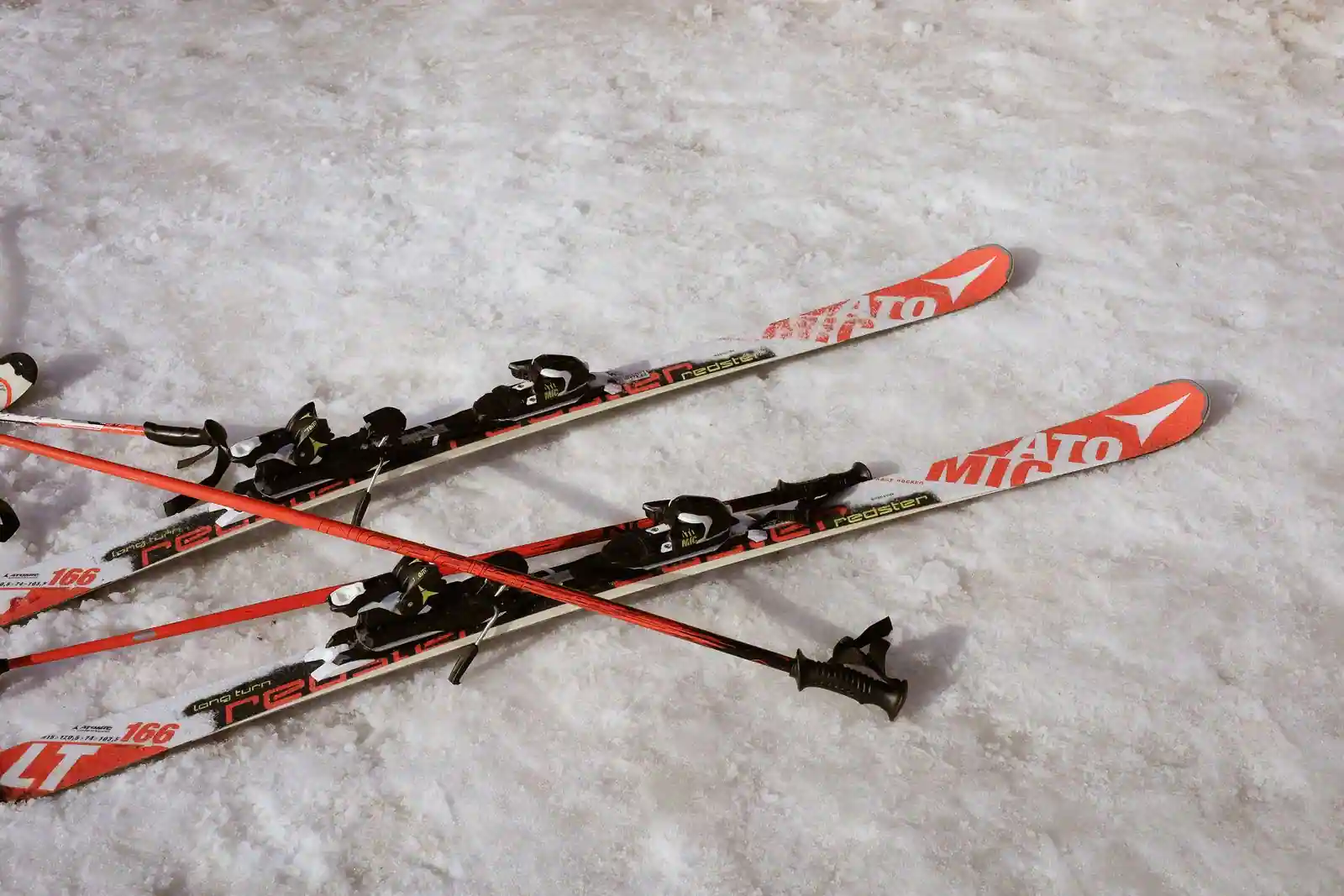 Paire de skis alpins et bâtons posés sur la neige, prêts pour une journée de glisse