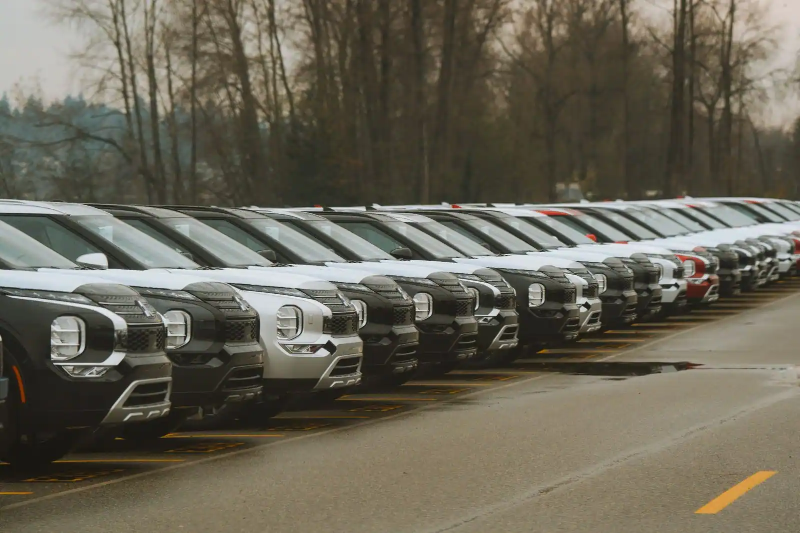 Longue rangée de voitures récentes alignées sur un parking extérieur, par temps couvert