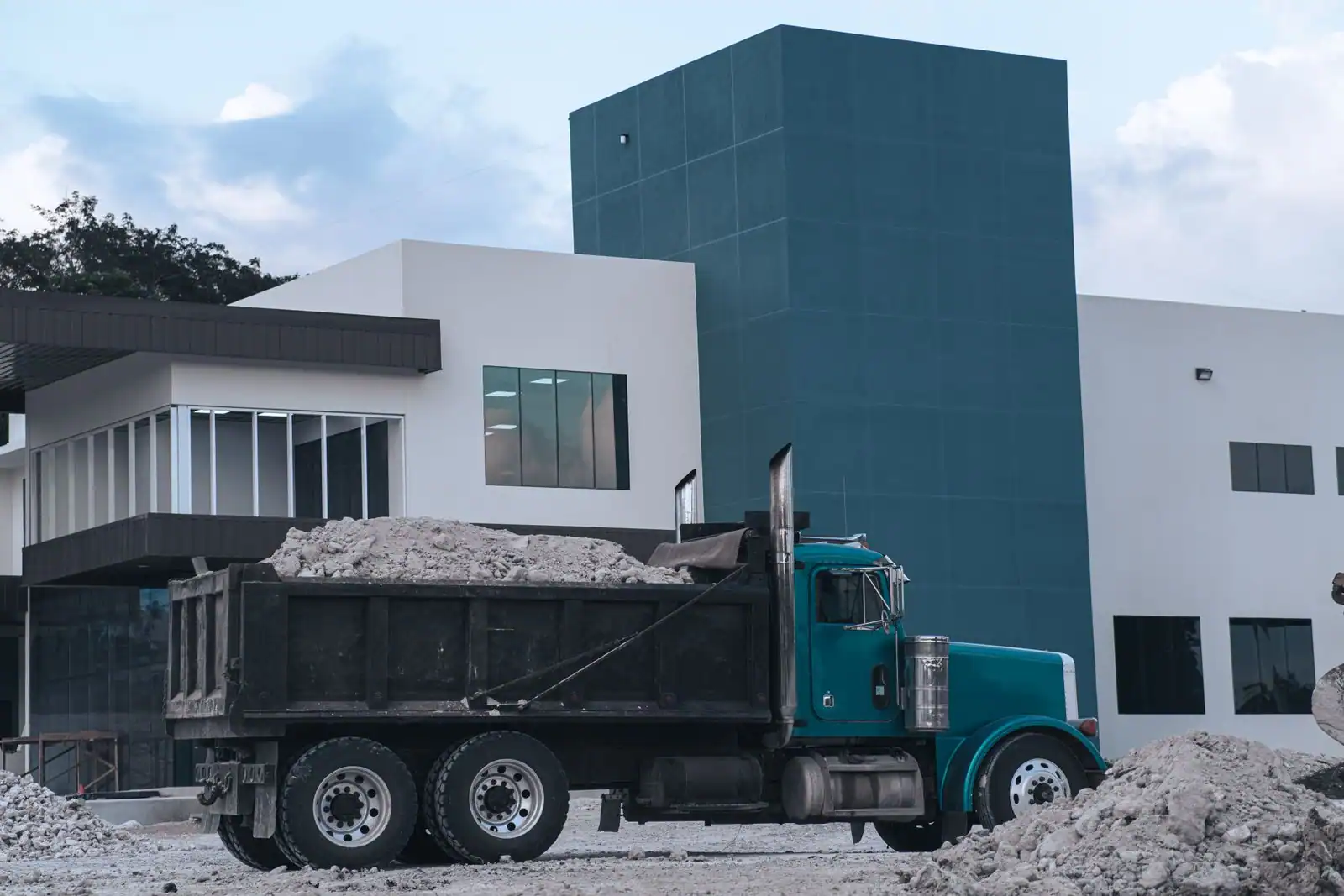 Camion benne chargé de gravats devant un bâtiment en chantier