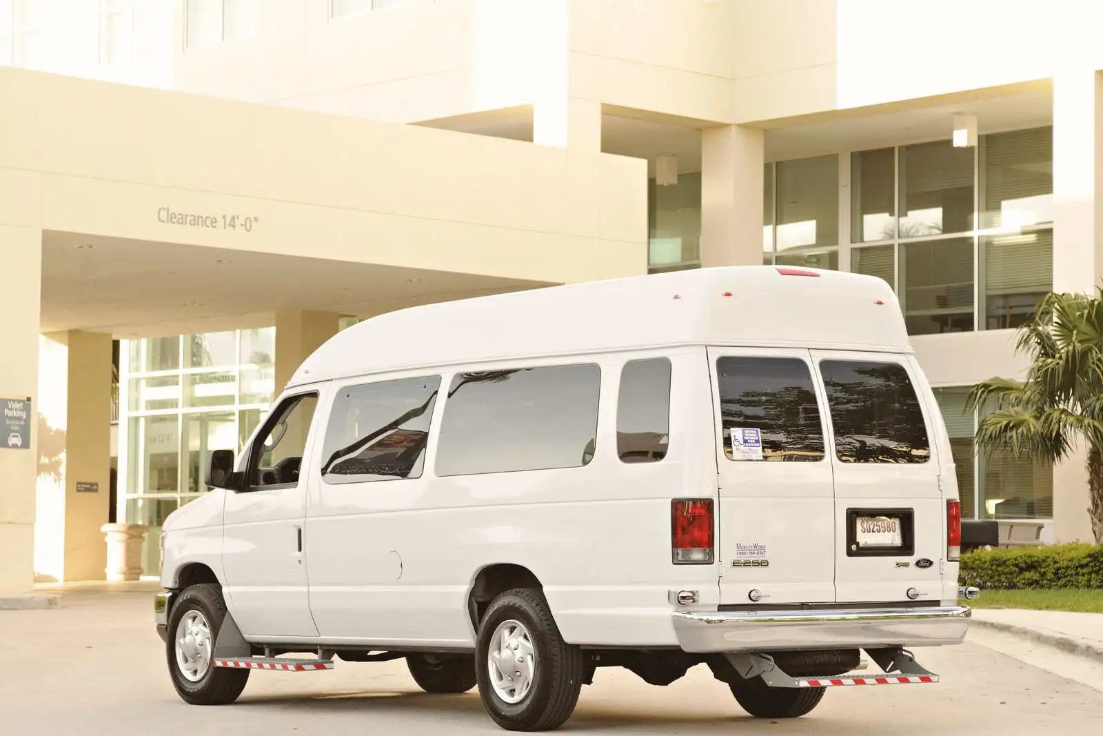 Minibus blanc stationné devant un bâtiment, prêt à accueillir un groupe