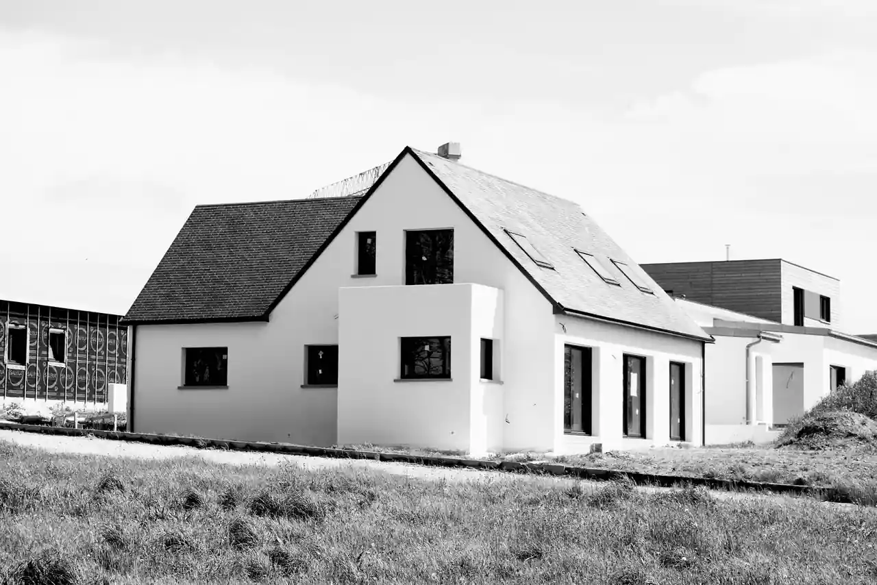 Maison individuelle neuve à façade claire et toiture en pente, vue de l’extérieur.