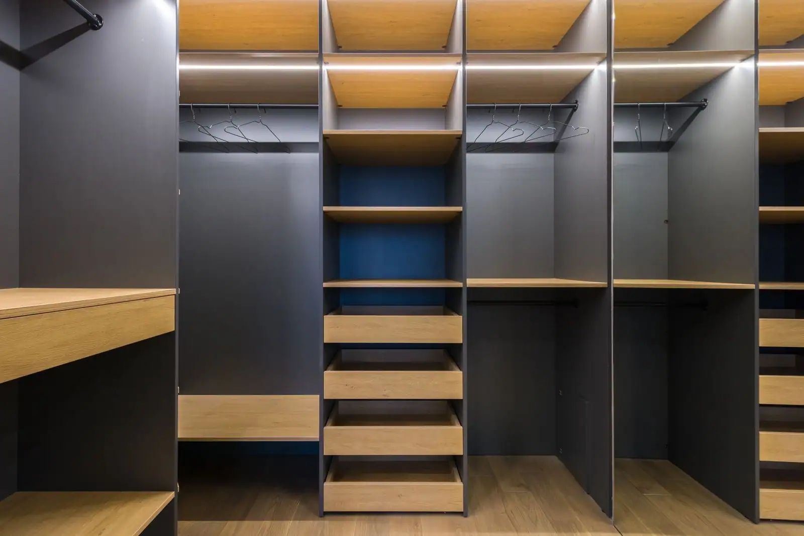 Dressing sur mesure avec étagères, tiroirs et penderies en bois aménagé dans une pièce