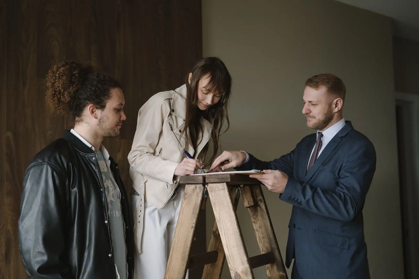 Couple signant un contrat d'achat immobilier avec un agent lors de la transaction