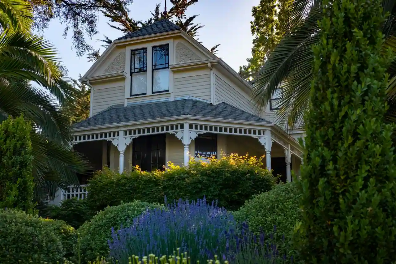 Maison individuelle traditionnelle avec porche, entourée d'un jardin arboré et de massifs de lavande