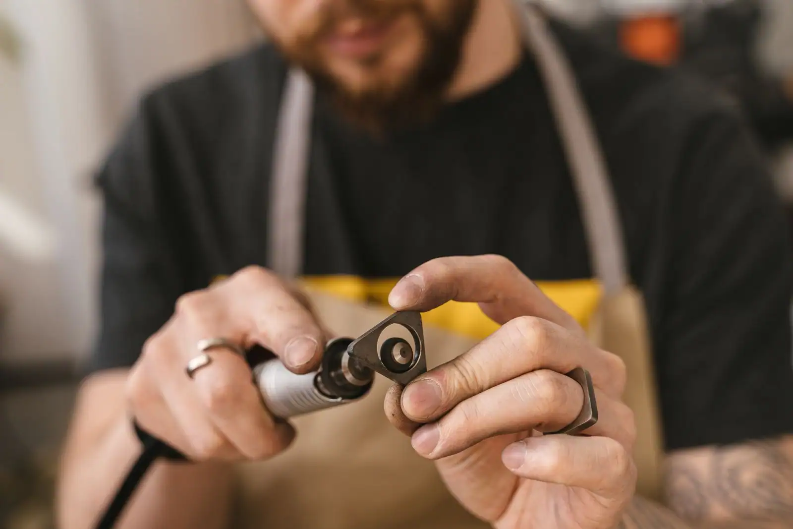 Artisan utilisant un outil rotatif équipé d'un petit disque pour un travail de précision sur métal