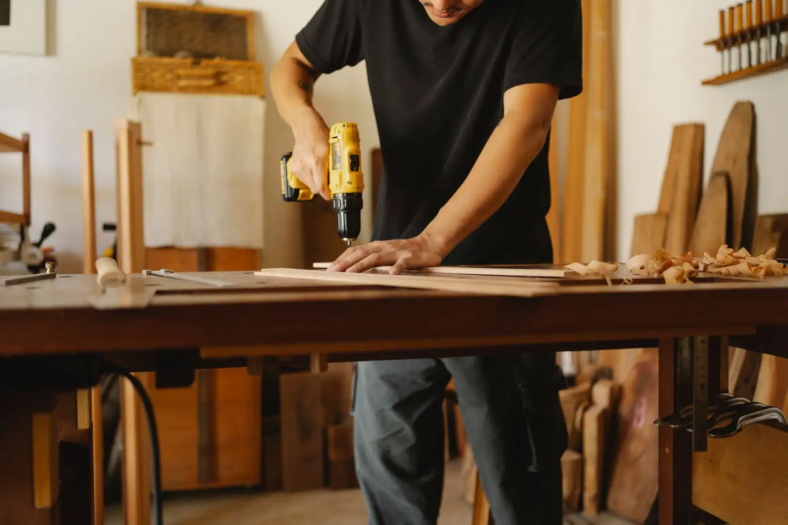 Artisan perçant une planche de bois à la perceuse électrique dans un atelier