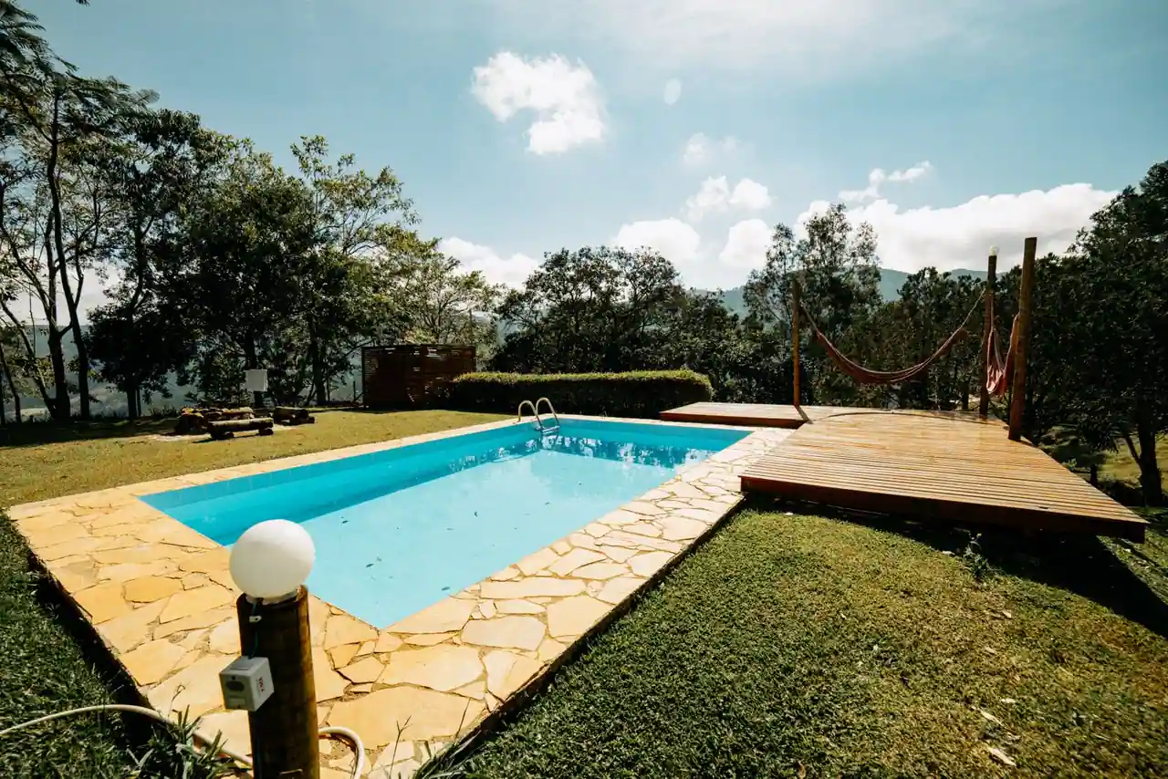 Piscine extérieure dans un jardin aménagé avec terrasse, sous un ciel dégagé.