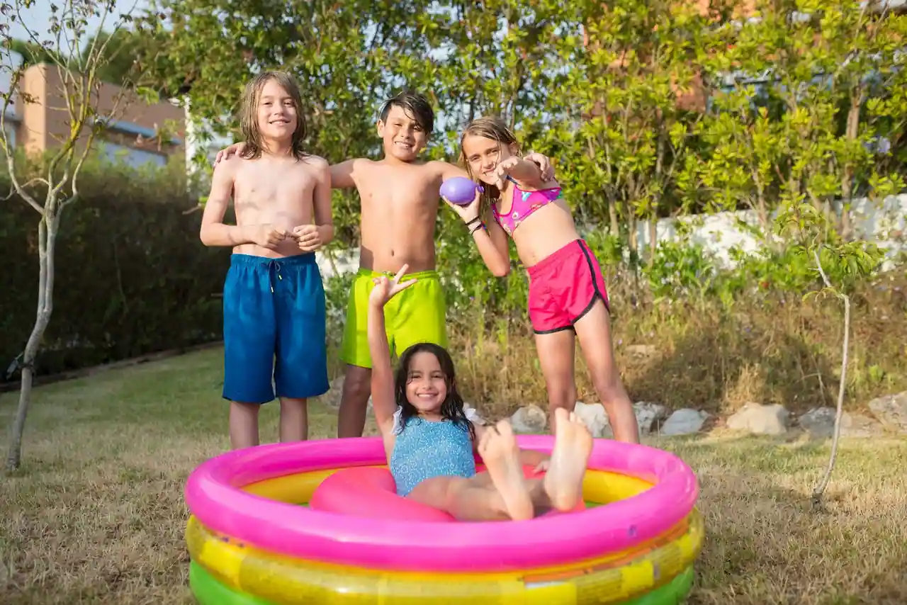 Piscine hors-sol gonflable installée dans un jardin, avec des enfants qui s'y baignent en été