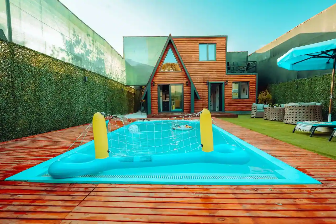 Piscine hors sol à parois bleues installée sur une terrasse en bois dans un jardin.