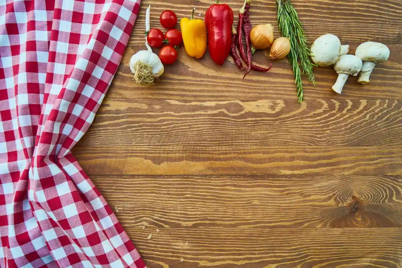 Assortiment de légumes frais du potager — tomates, poivrons, ail et oignon — sur une table en bois.