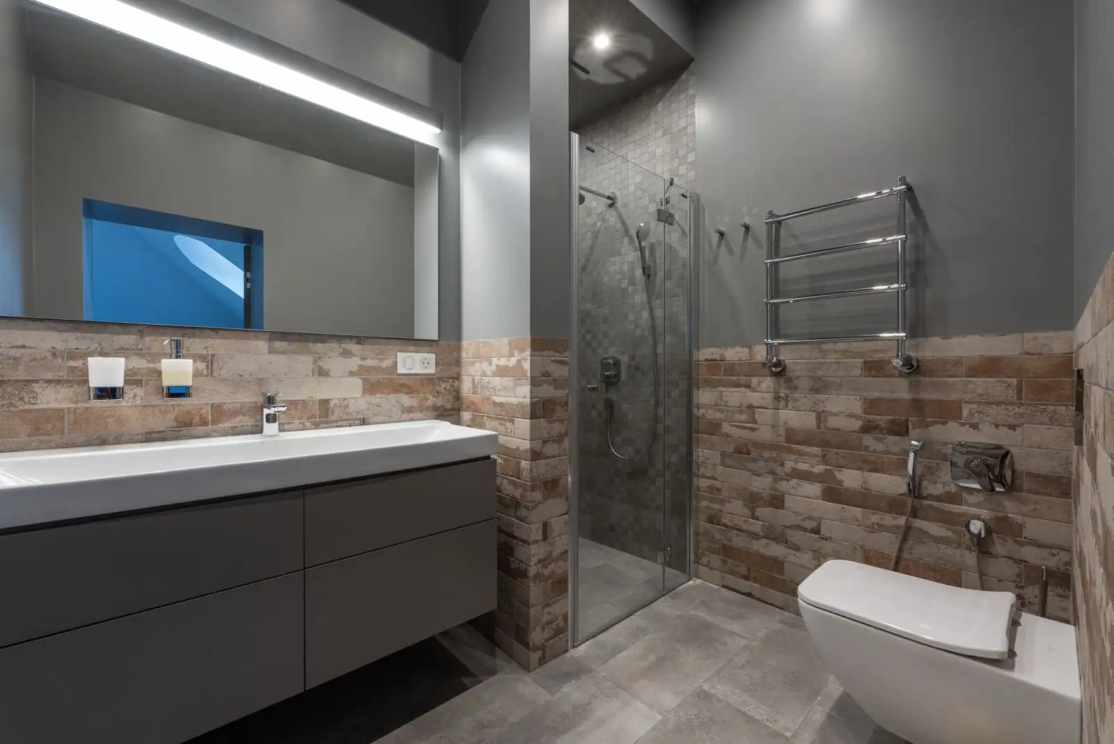 Salle de bain rénovée et lumineuse avec douche de plain-pied vitrée et meuble vasque suspendu.