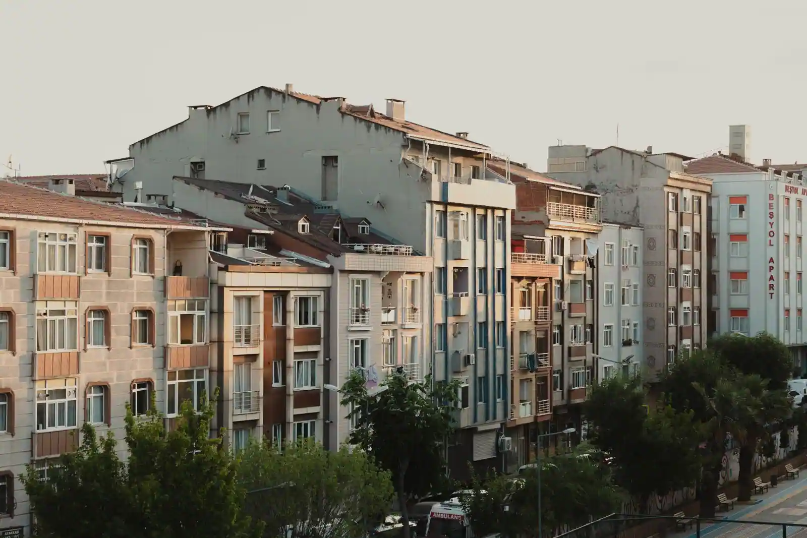 Rangée d'immeubles résidentiels aux façades alignées le long d'une rue de ville, en fin de journée.