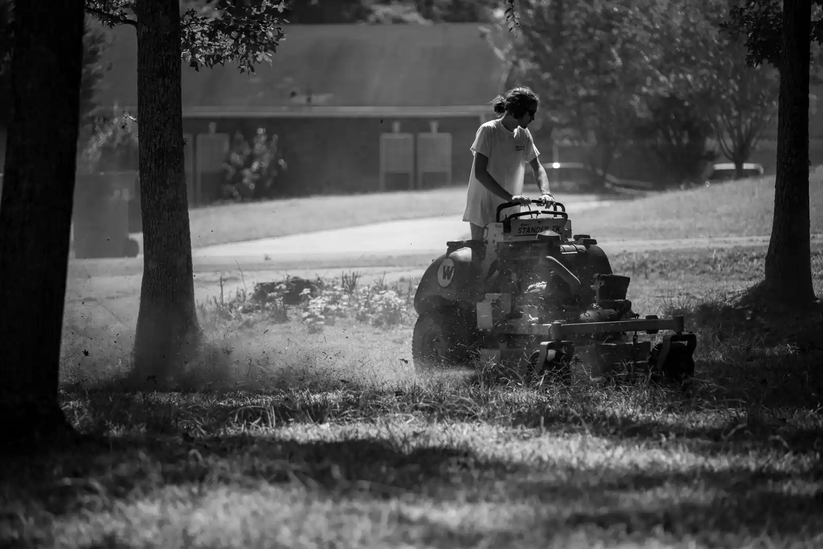 Personne tondant l'herbe d'un jardin à l'aide d'une tondeuse autoportée