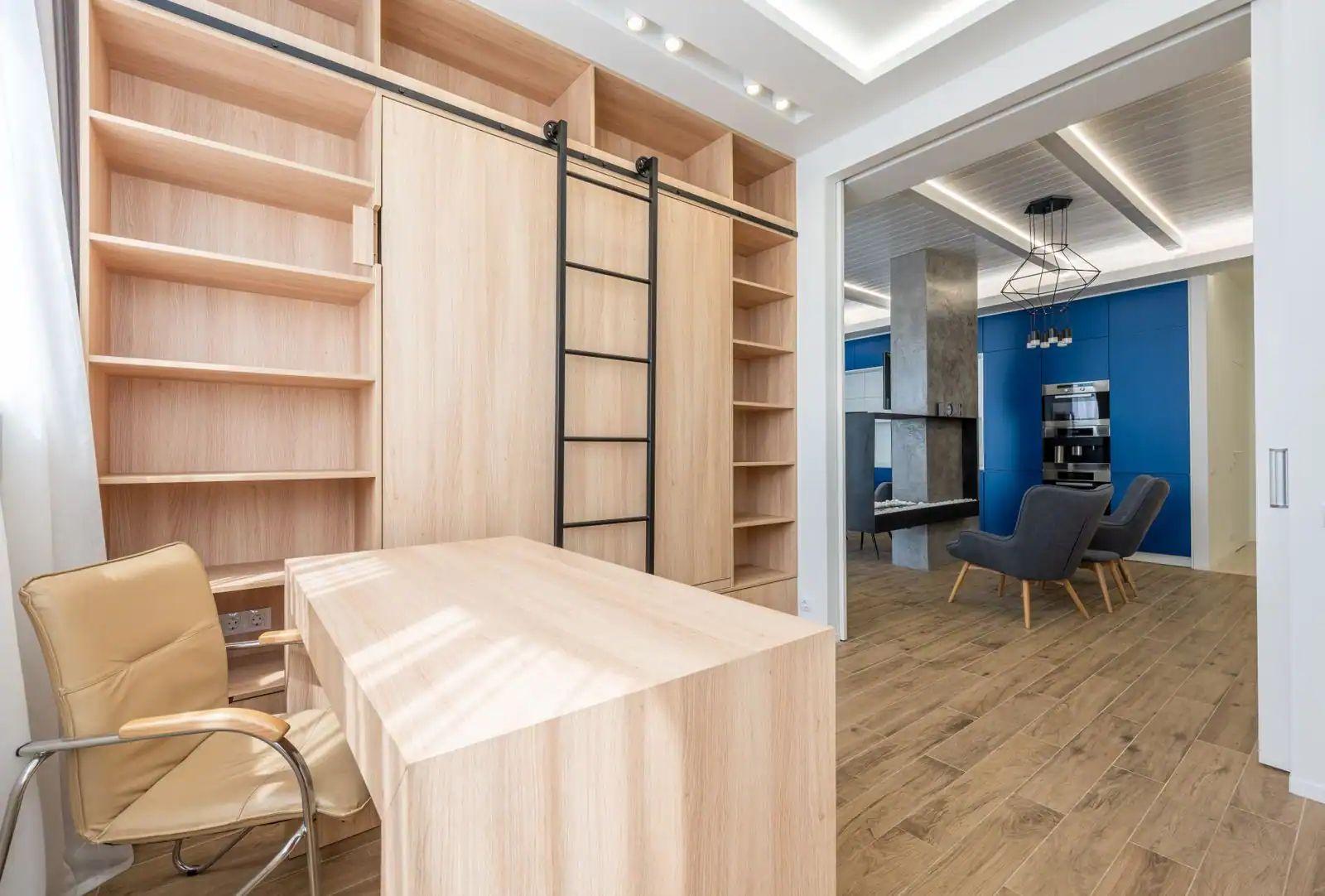 Pièce de travail aménagée dans un appartement, avec une table large, un fauteuil de bureau et une bibliothèque intégrée