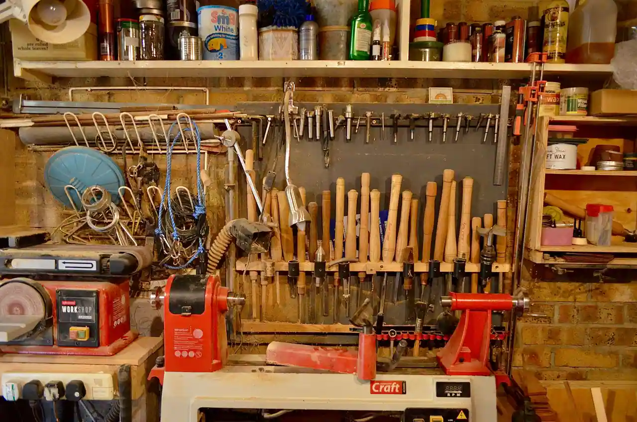 Atelier de bricolage équipé : râtelier de ciseaux à bois au-dessus d'un tour, outils rangés au mur.