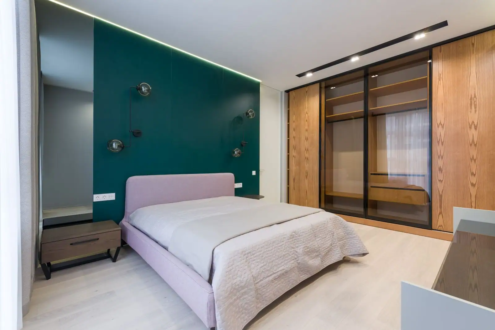 Chambre avec lit double, table de chevet, appliques murales et penderie intégrée aux portes coulissantes