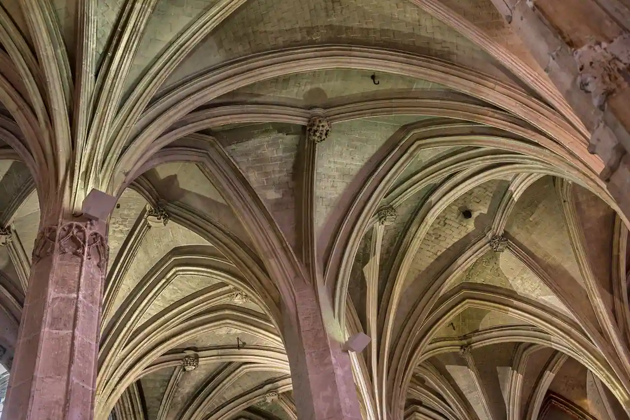 Voûtes sur croisées d'ogives en pierre, clés sculptées et colonnes vues depuis le sol