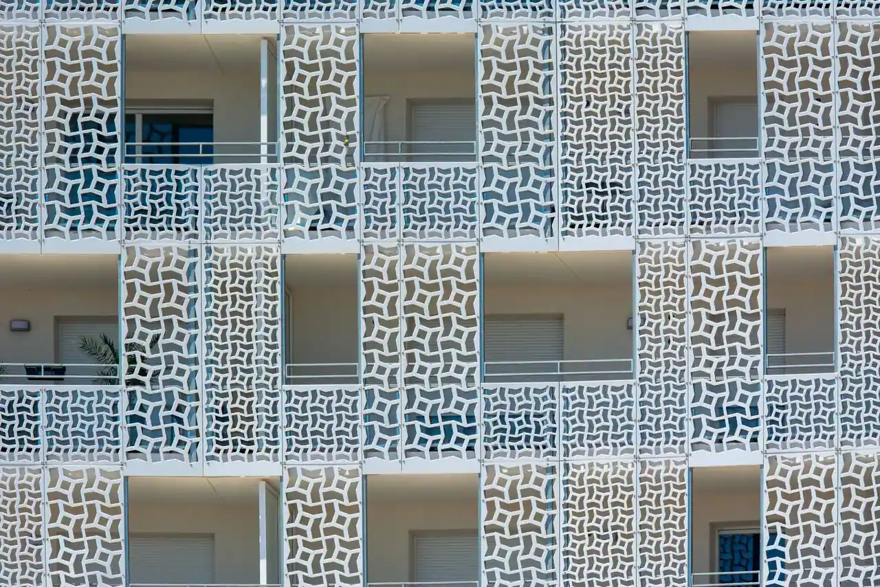 Façade d'immeuble d'habitation dont les balcons sont protégés par des panneaux ajourés blancs
