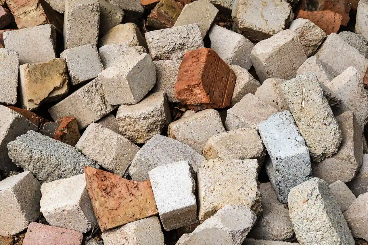 Gravats de démolition en tas : blocs de béton cassés et morceaux de briques rouges, vus de près