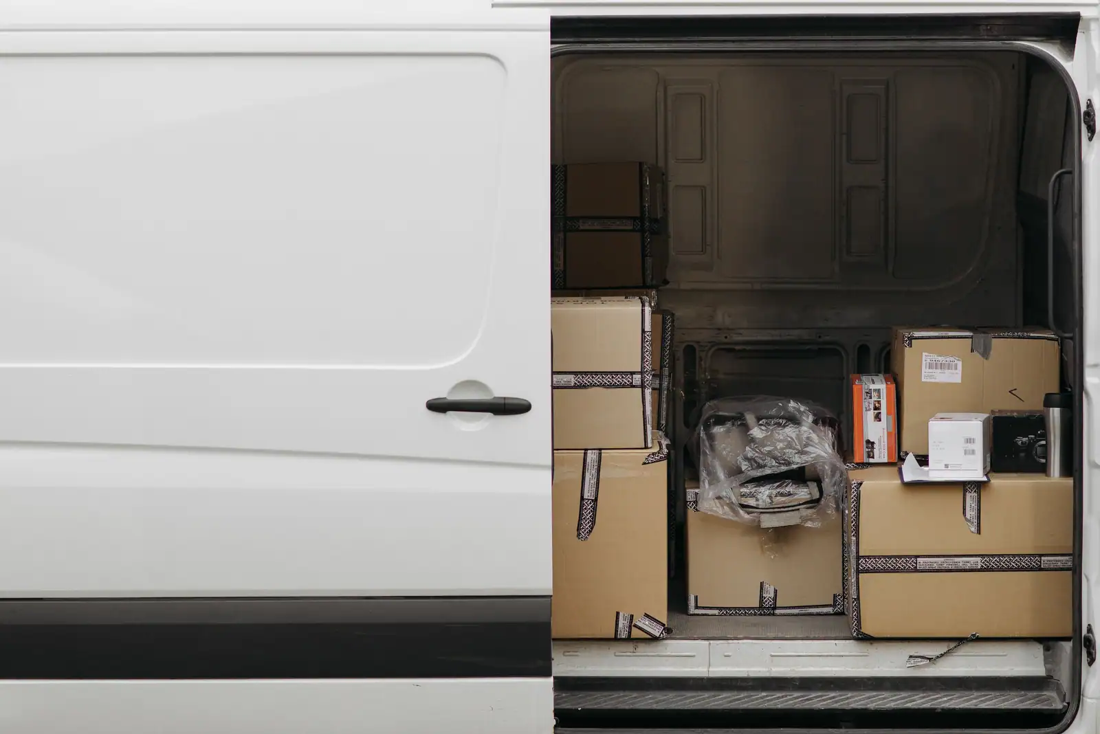 Porte latérale d’un fourgon utilitaire ouverte sur le volume de chargement, cartons empilés au plancher.