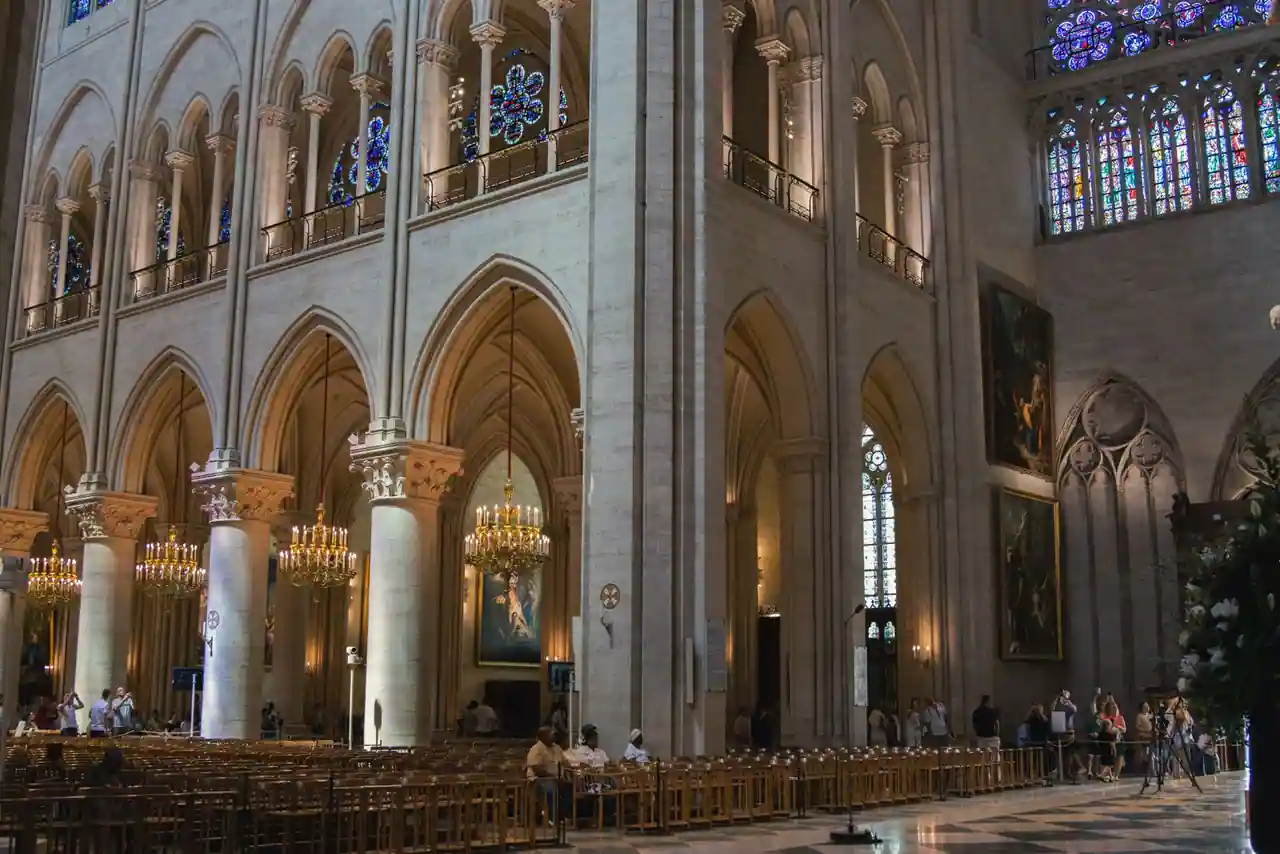 Nef gothique de Notre-Dame de Paris, hautes colonnes de pierre claire et rangées de chaises de bois