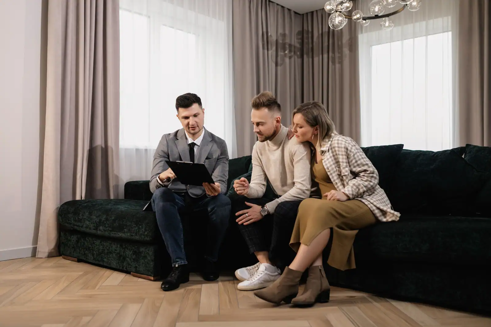 Un agent immobilier présente un document à un couple assis sur un canapé dans un salon