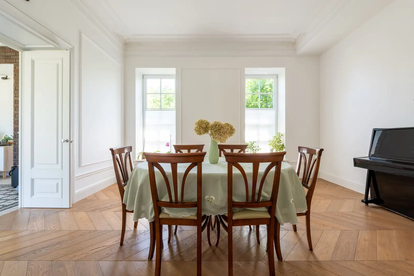 Salle à manger claire aux corniches moulurées et au parquet de chêne posé en chevrons.