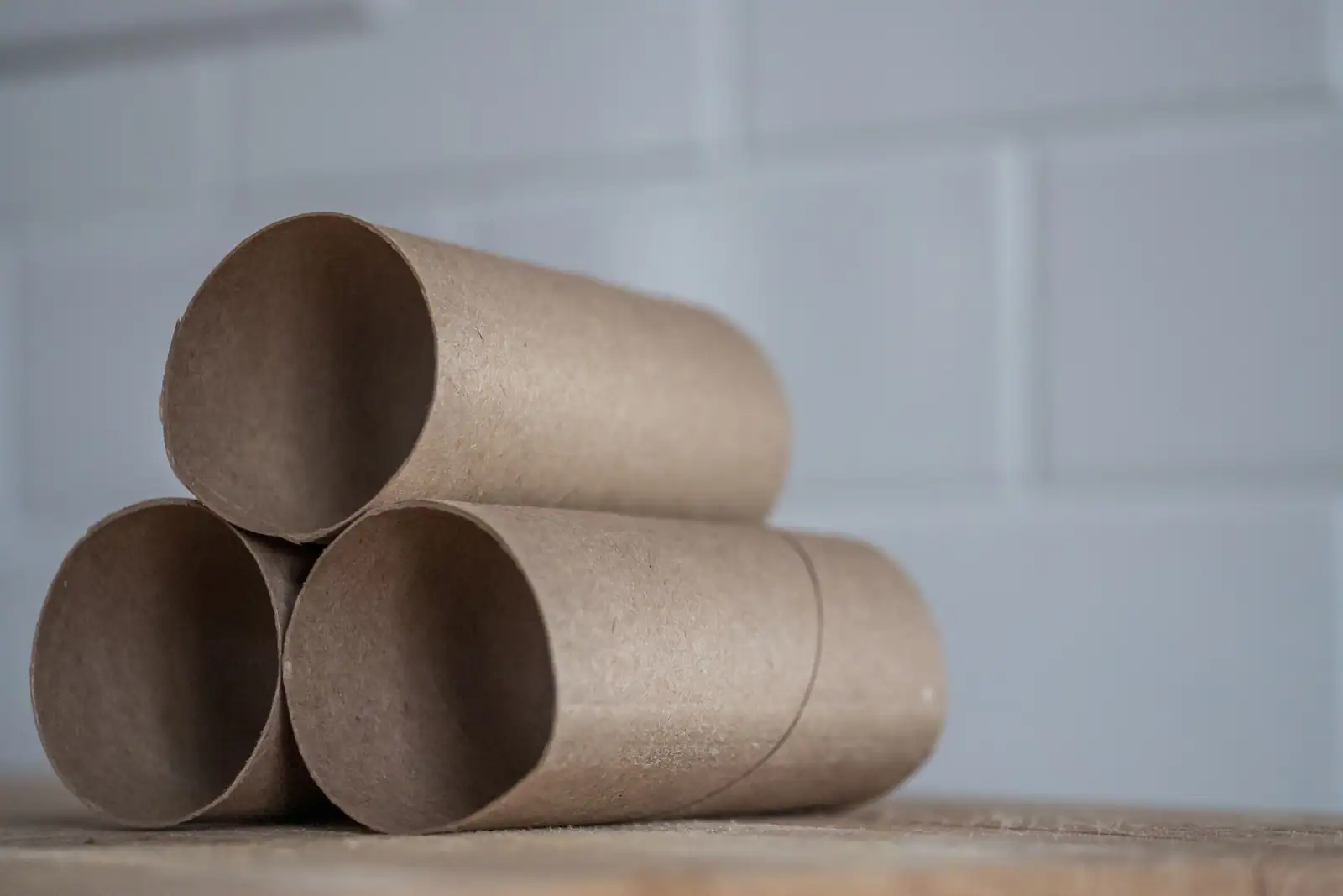 Trois rouleaux de papier toilette vides empilés sur un plan en bois, la spirale du carton bien visible