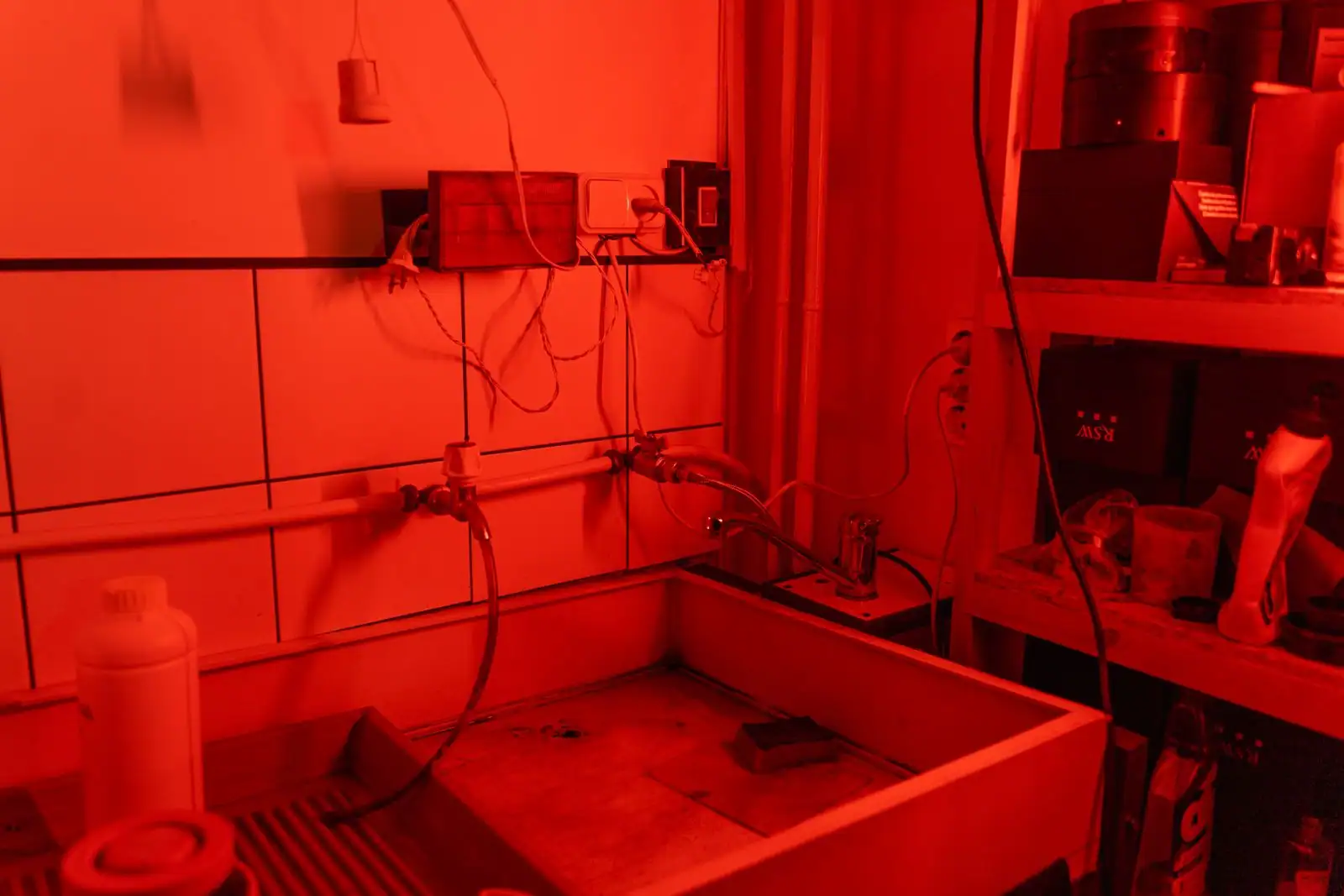 Bac de lavage et arrivées d'eau d'un laboratoire photo argentique sous lumière rouge inactinique
