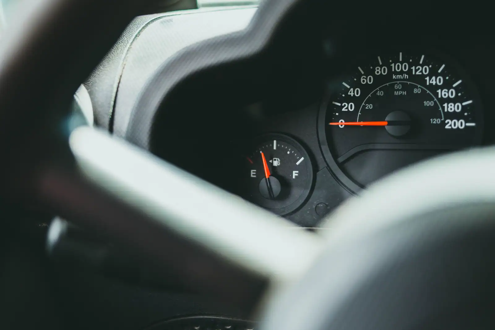 Combiné d'une voiture vu à travers le volant, compteur en kilomètres-heure et jauge de carburant sur la réserve.