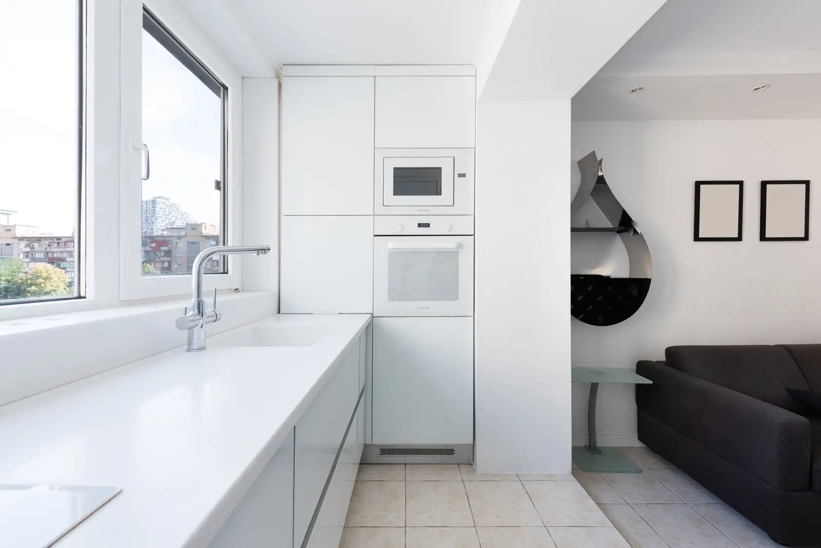 Coin cuisine linéaire le long d'une fenêtre, ouvert sur la pièce à vivre d'un petit logement